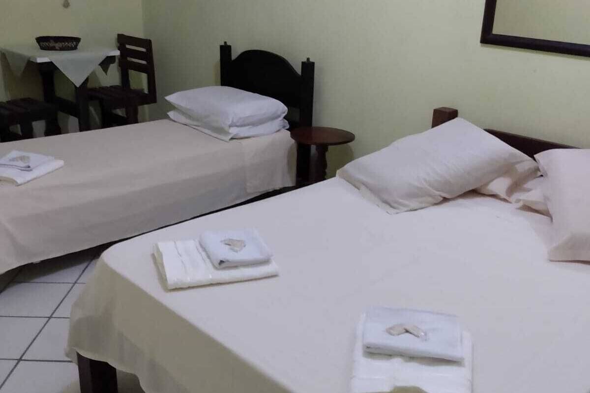 A hotel room with two beds, a small table, and a chair.