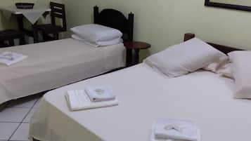 Quarto de hotel com duas camas, uma mesinha e uma cadeira.