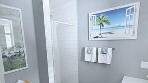 A bathroom with a toilet, shower, sink, and a wall-mounted towel rack. - Cozy spot next to Duval with swim spa - 2bed/2bath (Key West)