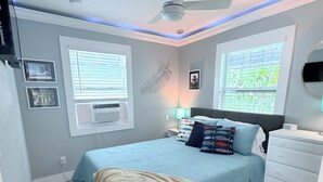 A bedroom with a bed, bedside tables, a ceiling fan, and windows. - Cozy spot next to Duval with swim spa - 2bed/2bath (Key West)
