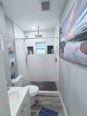 A modern bathroom with a shower, toilet, and sink.