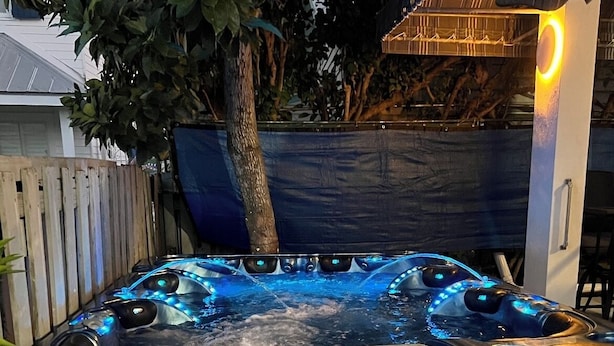 A hot tub with multiple jets, surrounded by a wooden fence and a tree. - Cozy spot next to Duval with swim spa - 2bed/2bath (Key West)