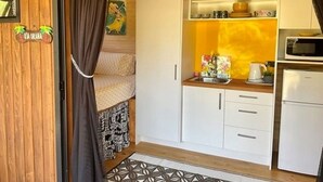 A compact kitchen with white cabinets, a microwave, and a coffee maker. - Are Mii , a stylish one room container home (Arorangi District)