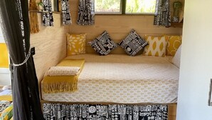 A small, cozy room with a bed, patterned pillows, and curtains. - Are Mii , a stylish one room container home (Arorangi District)