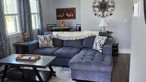 Ein Wohnzimmer mit grauem Sofa, Couchtisch und Deckenventilator.