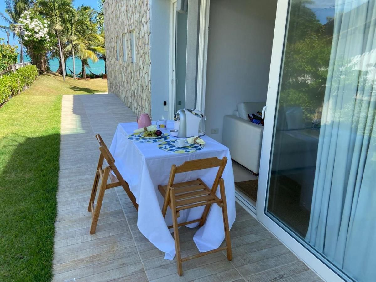 Uma área de refeições ao ar livre com uma mesa posta para dois, uma cadeira e uma porta de vidro que dá para um alpendre coberto.