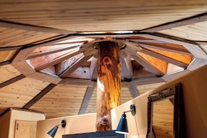Techo de madera con una viga central, una lámpara y una puerta.