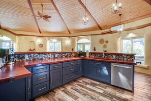 A spacious kitchen with dark cabinets, wooden countertops, and a large island.