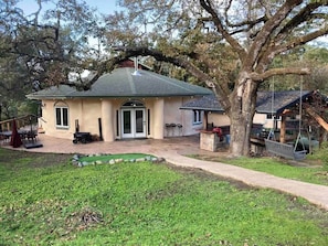 Une maison avec un patio couvert, une pelouse et une balançoire.