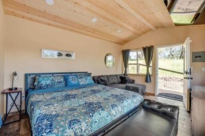 Una camera da letto con un letto grande, un divano, un tavolino e una finestra con tende.