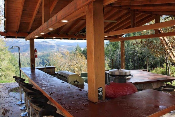 Cocina al aire libre techada con vistas a montañas, un extintor y una parrilla.