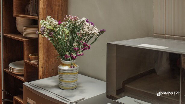 Eine Küchenzeile mit einem Holsschrank, einer weißen Arbeitsplatte und einer Vase mit Blumen.