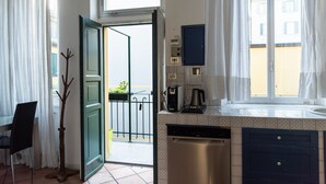 A kitchen with a dishwasher, a coffee maker, and a window with curtains.