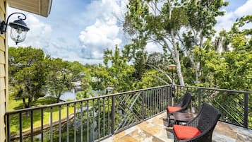 Enjoy the serene views of the water and lush surroundings from this balcony.