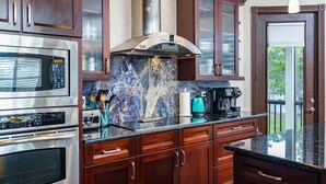 A modern kitchen with stainless steel appliances, dark wooden cabinets, and a marble backsplash. - Bigfoot Bungalow -Enjoy being directly on clear waters of the Weeki Wachee River (Weeki Wachee)