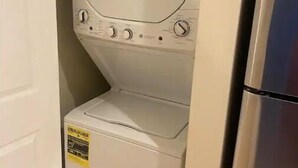 A compact washer and dryer unit with a stainless steel refrigerator adjacent to it.