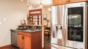 A modern kitchen with wooden cabinets, a stainless steel refrigerator, and a dishwasher.