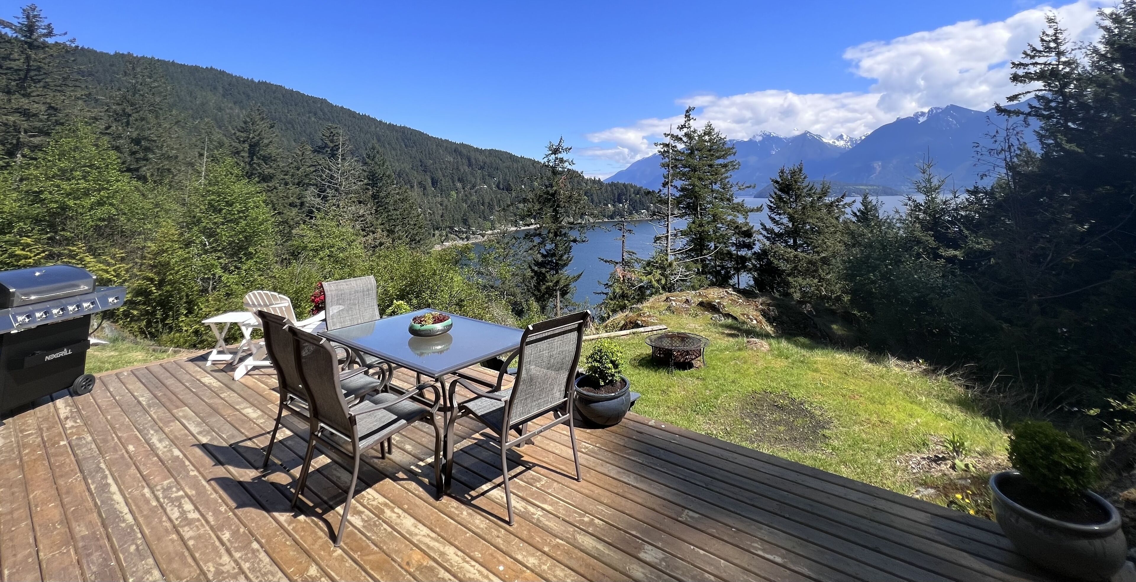 Una terraza con mesa y sillas con vistas a un lago y montañas.