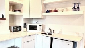 A compact kitchen with white cabinets, a microwave, a toaster, and a sink.