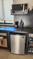 Una cocina compacta con lavavajillas de acero inoxidable, un microondas y una cafetera sobre la encimera.