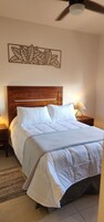 Una cama bien hecha con ropa blanca, un cabecero de madera y un adorno decorativo encima.