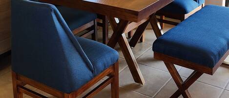 A dining area with a wooden table, blue upholstered chairs, and a potted plant.