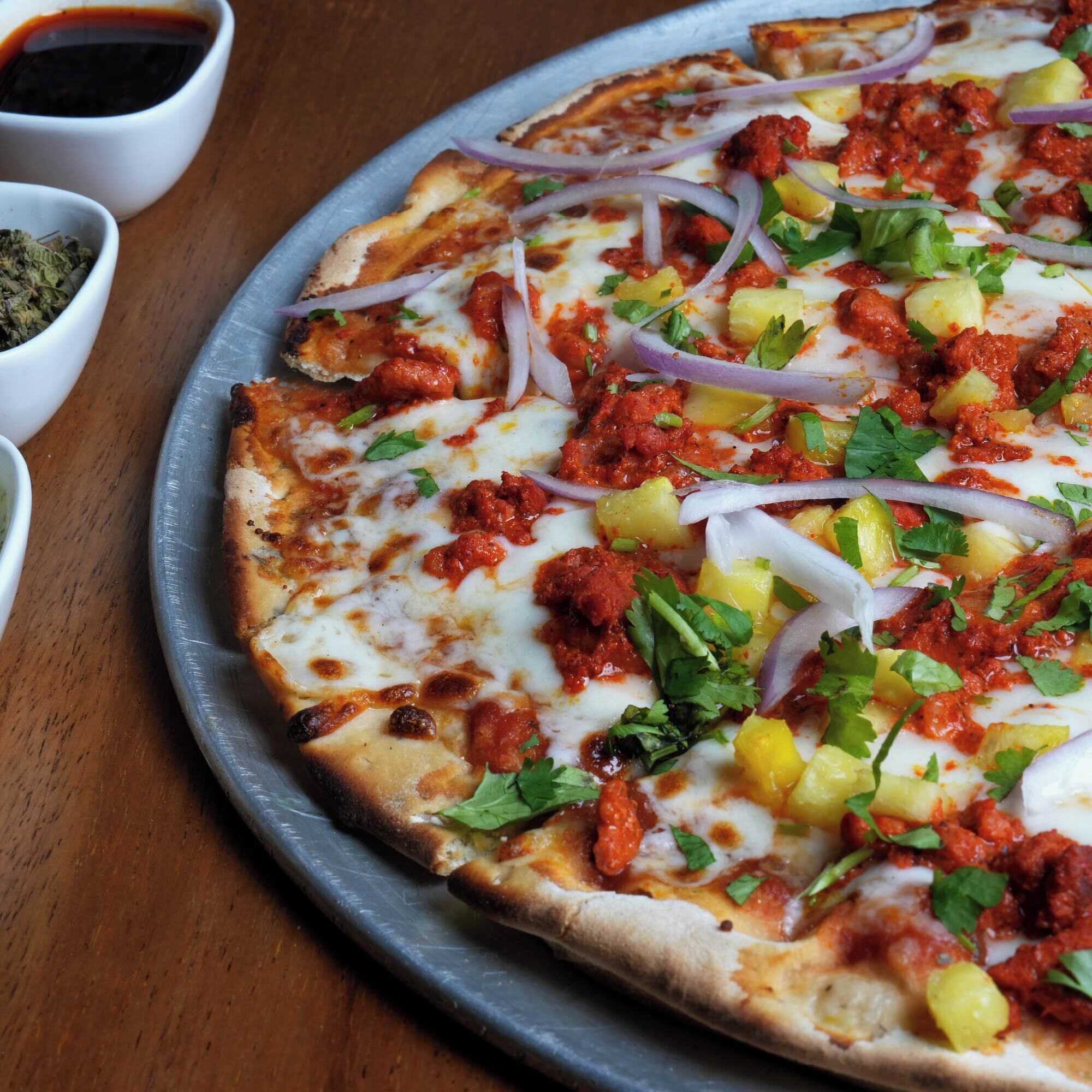 Une pizza garnie, servie sur un plateau en métal.