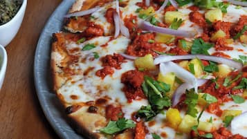 Una pizza con ingredientes sobre una bandeja metálica.