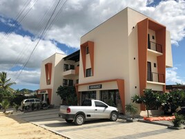 Un edificio moderno de varios pisos con un centro comercial llamado 'MINIMARKET' en la planta baja.