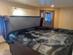 A hot tub with a control panel, a towel rack, and a door leading to an outdoor area.