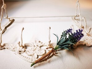 A decorative white metal stand with a floral design and a bundle of purple flowers.