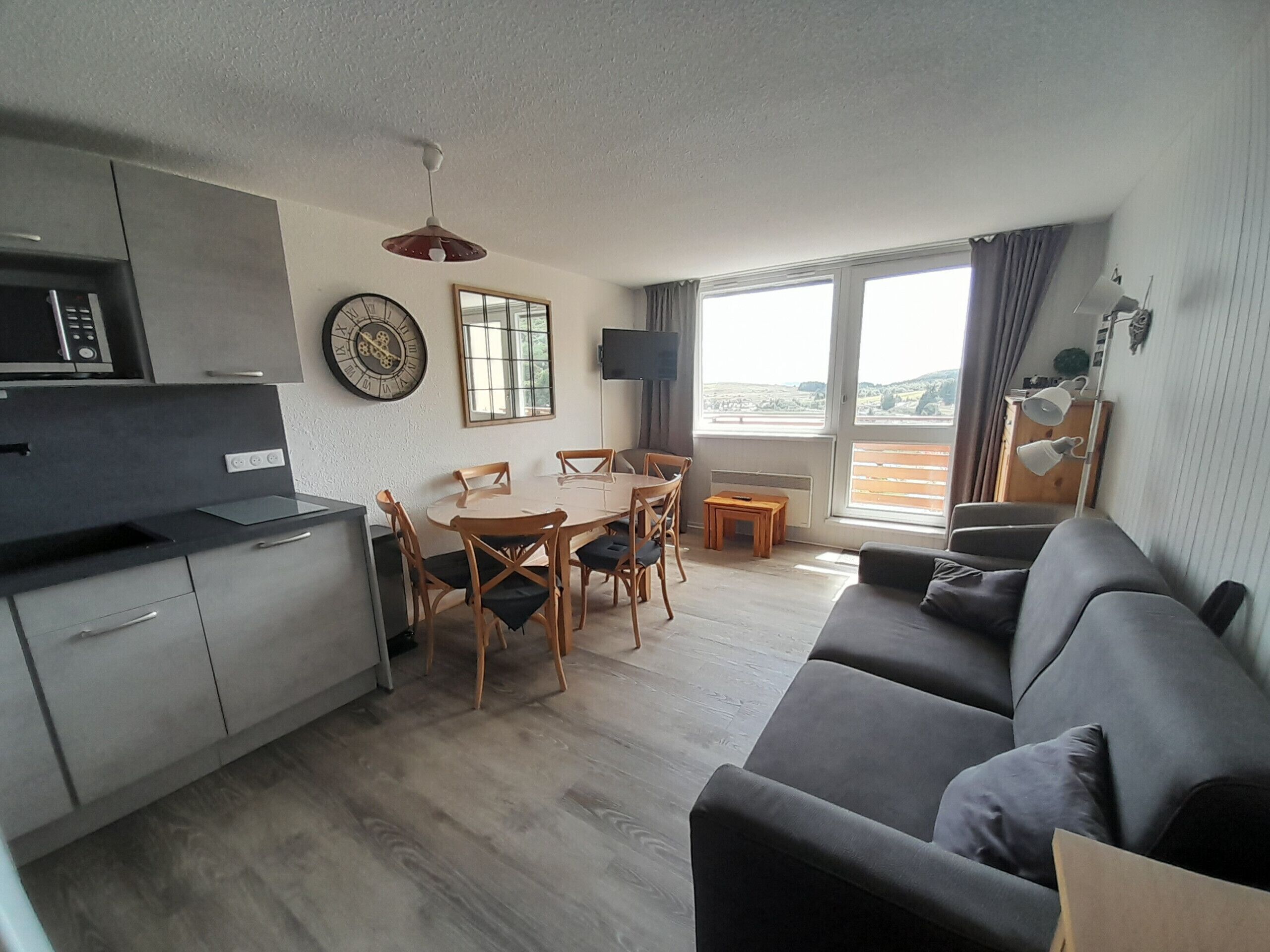 A modern living space with a kitchen, dining area, and a sofa.
