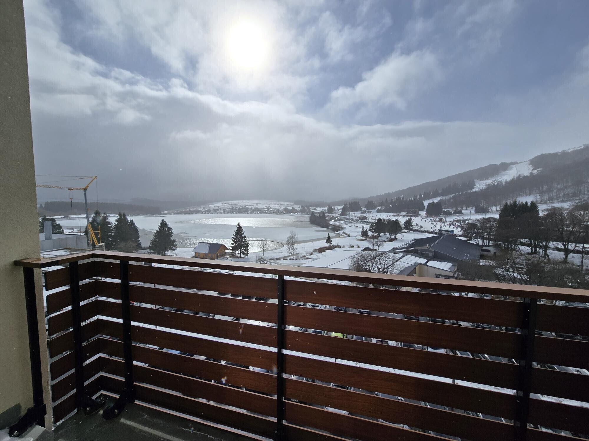 A balcony with a view of a snowy landscape, including a body of water and distant buildings.