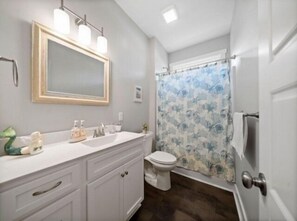 A bathroom with a white vanity, a mirror, and a shower curtain with a floral pattern.