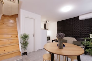 Cozinha moderna com escada de madeira, área de jantar com mesa redonda e parede preta texturizada.