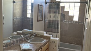 Une salle de bain avec deux lavabos, une baignoire et une douche.