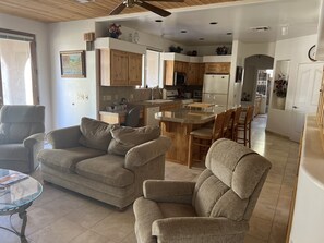 A modern living room with a sofa, armchairs, and a glass coffee table.