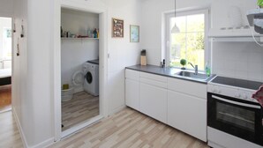 Una cocina moderna con lavadora integrada, un lavamanos y una estufa.