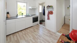 Una cocina moderna con armarios blancos, horno empotrado y ventana que ofrece luz natural.
