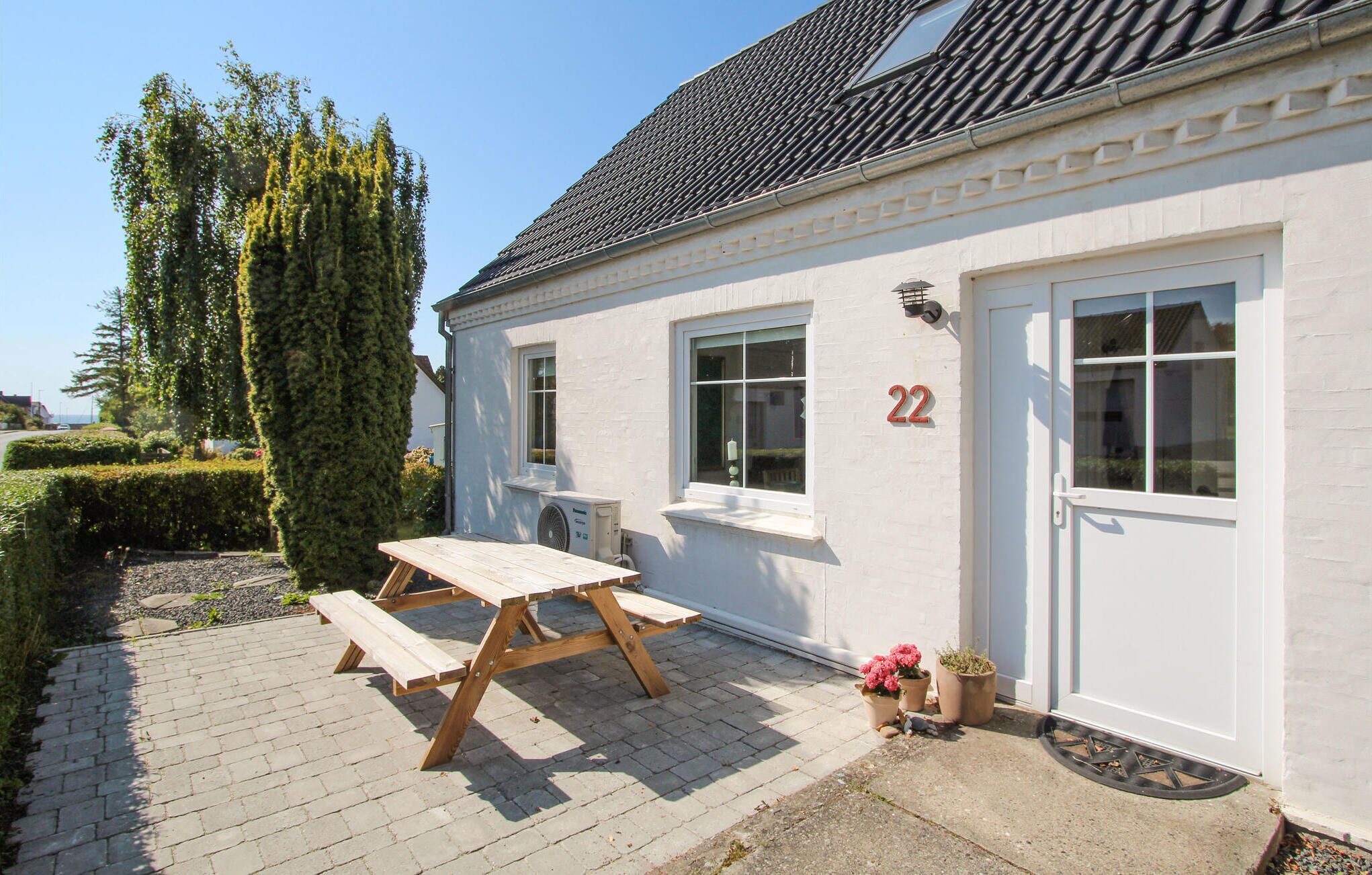 A white building with the number 22, a wooden bench, and potted plants.