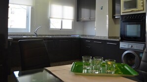 A compact kitchen with a sink, cabinets, a microwave, an oven, and a washing machine.