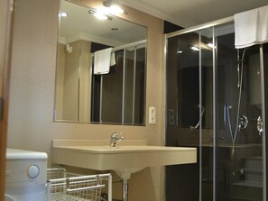 Un bagno con lavandino, specchio e cabina doccia in vetro.