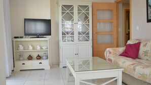 A living room with a TV, a glass coffee table, a sofa, and a cabinet with glass doors.