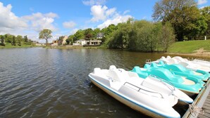 A calm lake with paddle boats docked at a wooden pier. - Leocadie - Plenee Jugon (PLENEE JUGON)