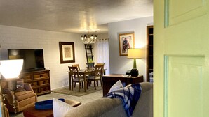 Una sala de estar con sofá, televisor, mesa de comedor y sillas.