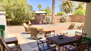 Un patio al aire libre con muebles de mimbre, una mesa y un tapete estampado.