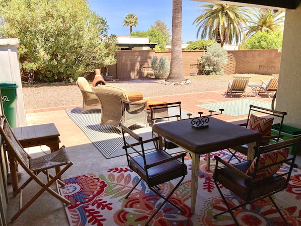Une terrasse extérieure avec des meubles en osier, une table et un tapis à motifs.