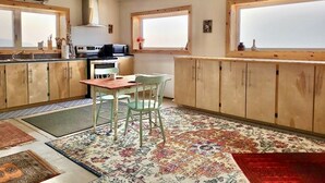Une cuisine avec des meubles en bois, une table à manger avec des chaises et une grande fenêtre qui laisse entrer la lumière naturelle.