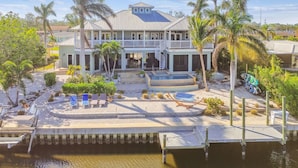 A large house with a pool, a dock, and a staircase leading to the upper floor.