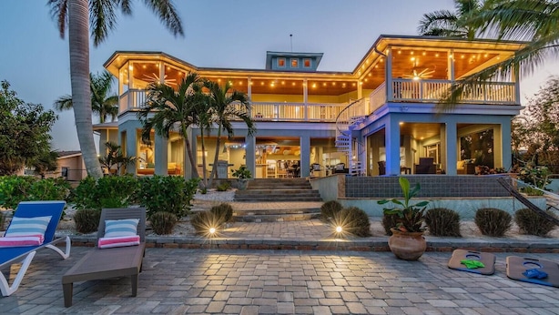 A two-story house with a covered porch, outdoor seating, and a staircase leading to the entrance.